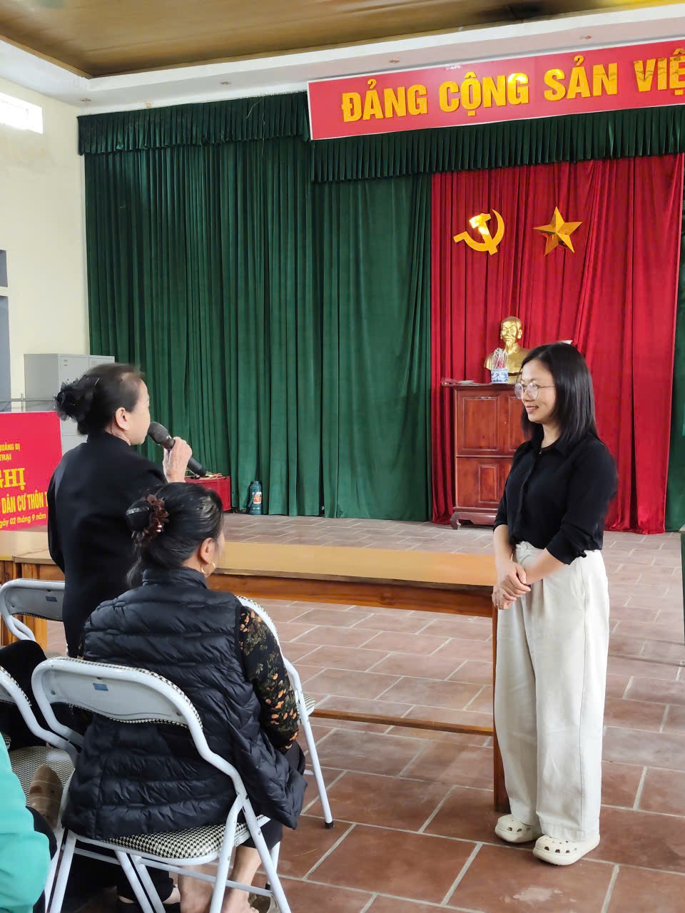 A person standing in front of a stage with a microphone  AI-generated content may be incorrect.