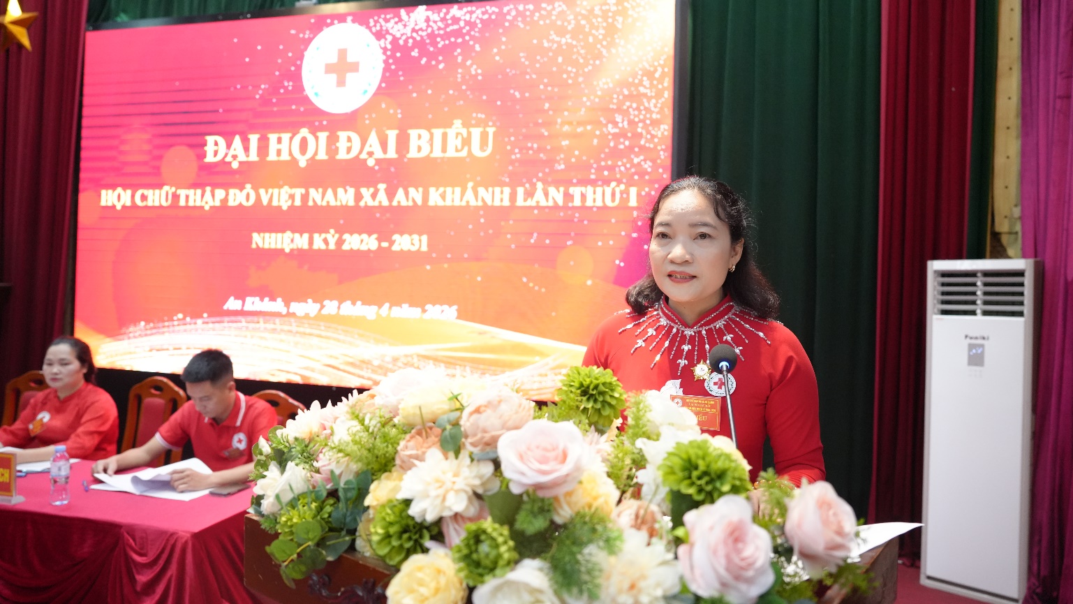 A person and person standing in front of a stage with flowers  AI-generated content may be incorrect.