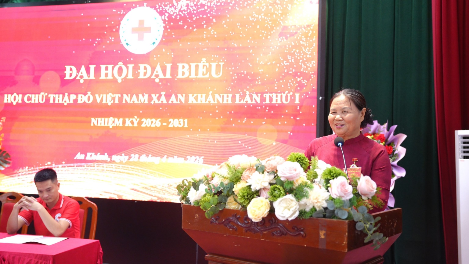 A person standing at a podium with flowers  AI-generated content may be incorrect.