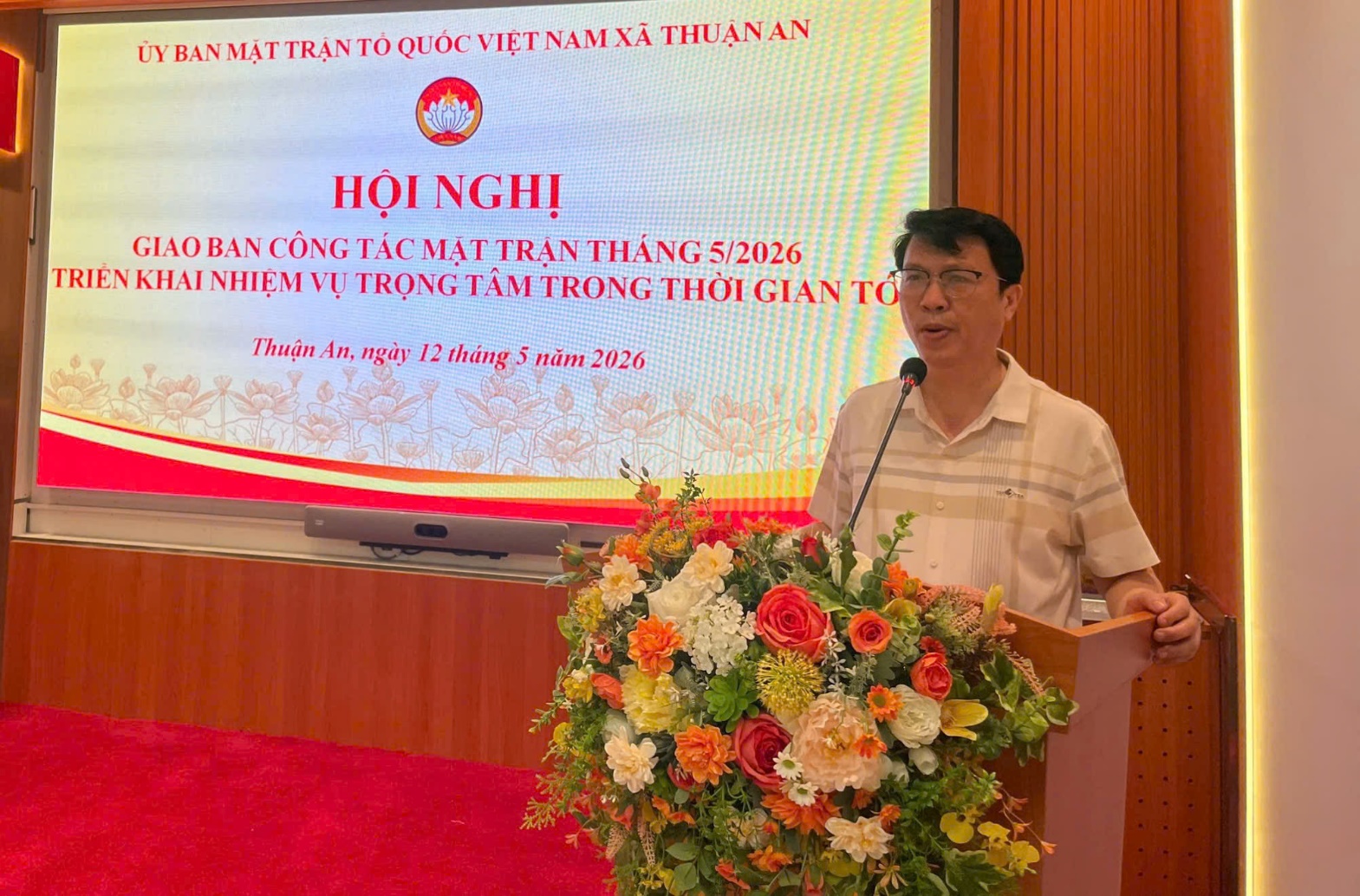 A person standing at a podium with a microphone and a large bouquet of flowers  AI-generated content may be incorrect.