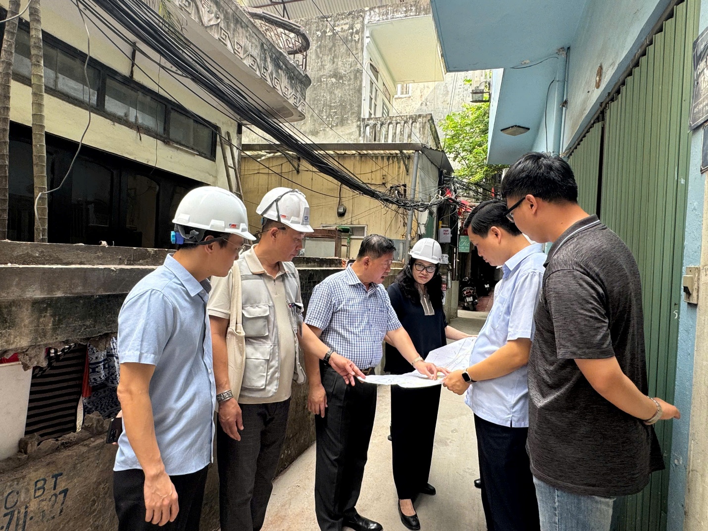 A group of people wearing hard hats looking at a blueprint  AI-generated content may be incorrect.