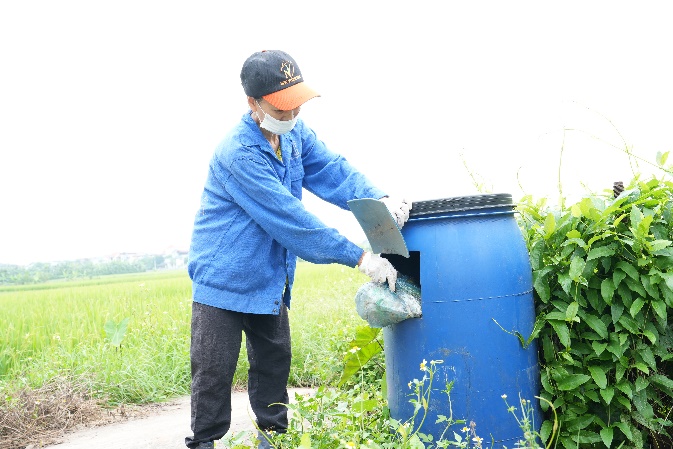 A person putting garbage into a blue barrel  AI-generated content may be incorrect.