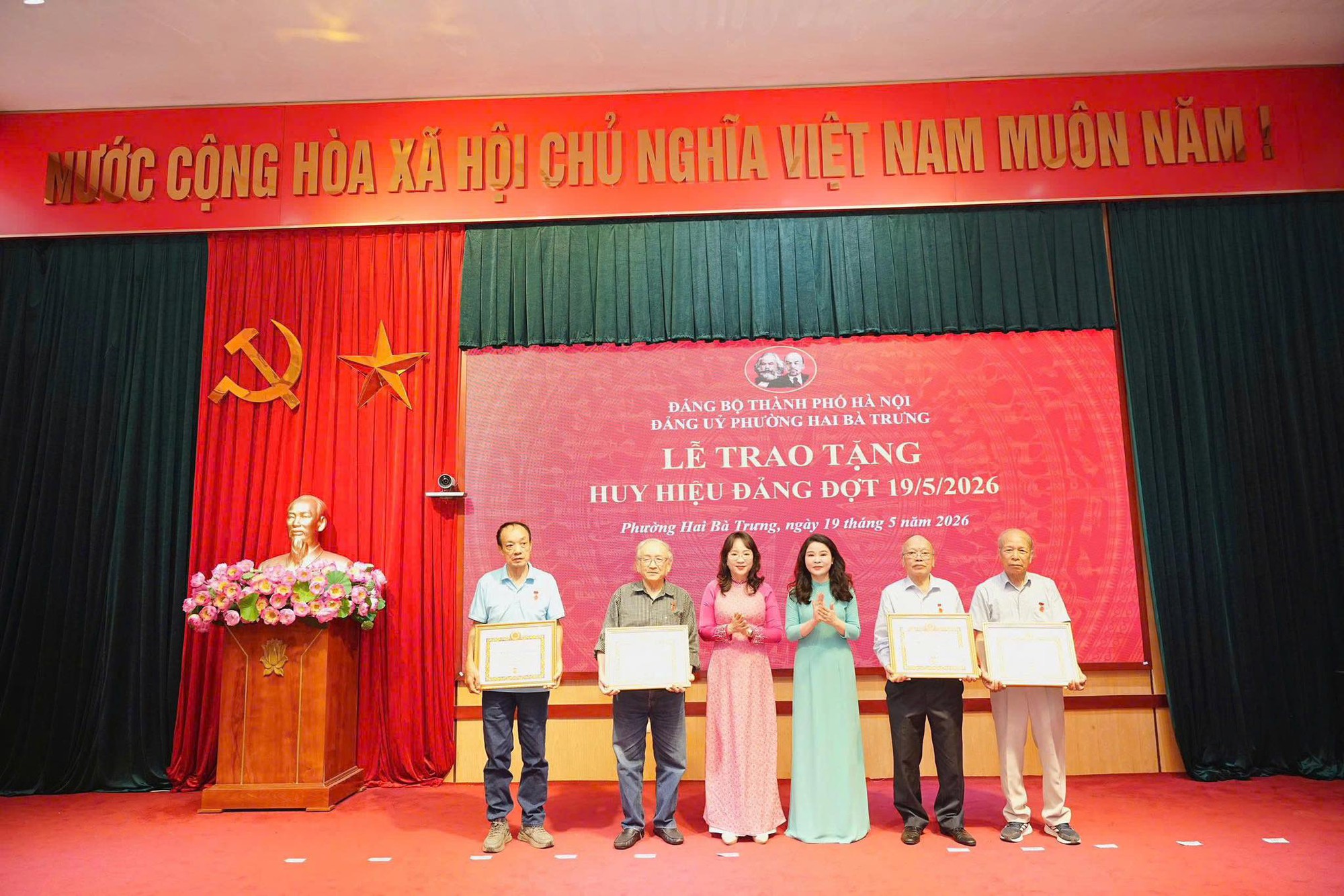 Có thể là hình ảnh về một hoặc nhiều người, cái bục và văn bản cho biết 'MƯỚC CỘNG HÒA XÃ HỘI CHỦ NGHĨA VIỆT NAM MUÔN NĂM: ĐẢNG BỘ THÀNH PHO ĐÁNGBOTHANHPIOHÀNOI HA NỘI ĐANG τν UY PHƯỞNG HAIB TRUNG LE TRAO LETRAOTANG ETRAOTẶNG TÀNG HUY HIỆU ĐANG DỢT 19/5/2026 Phưng Hai Bà à Trung, ngày tháng năm 2026'