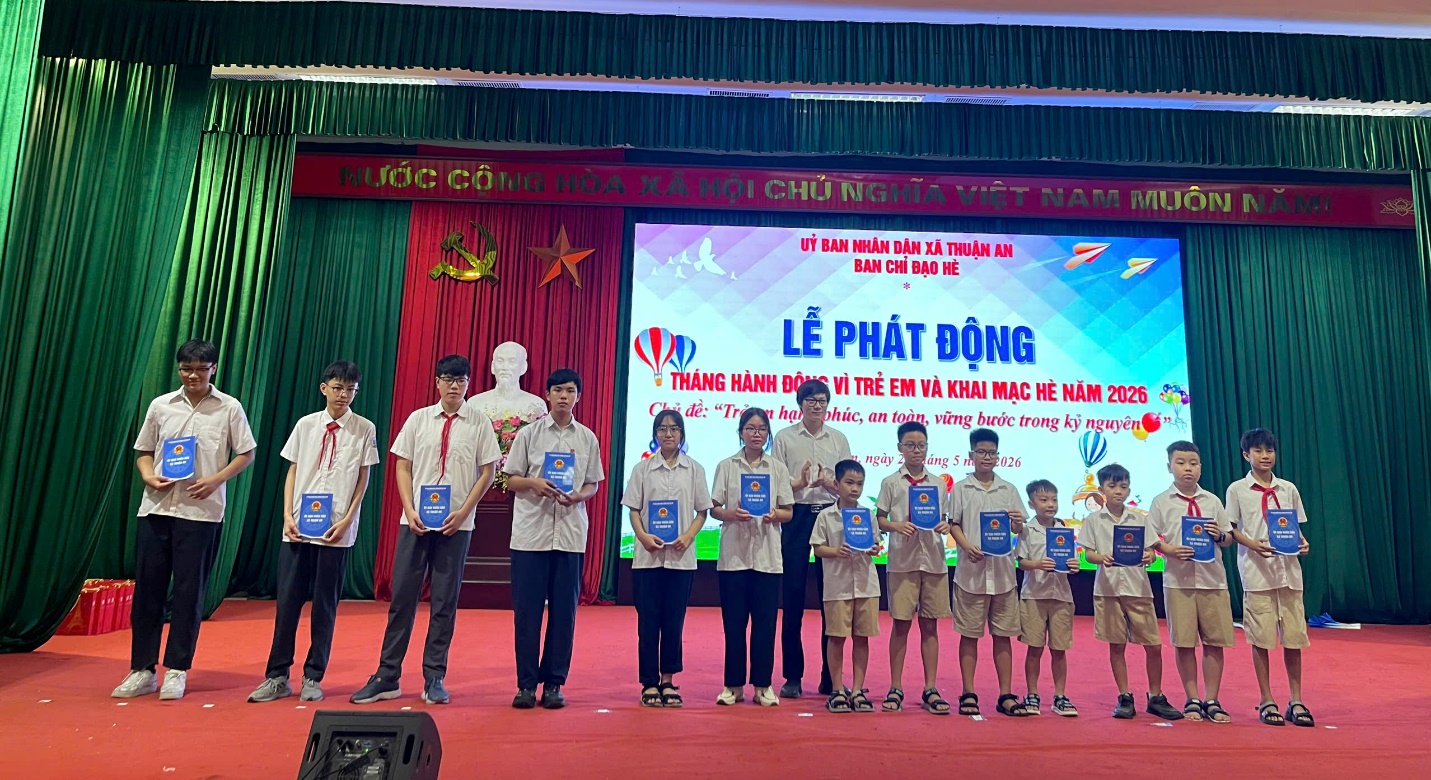 A group of people standing on a stage holding blue signs  AI-generated content may be incorrect.