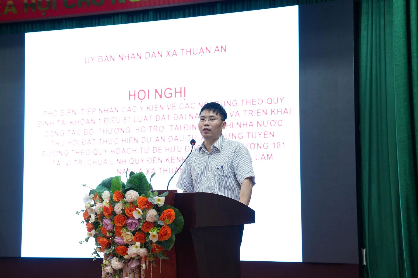 A person standing at a podium with a microphone  AI-generated content may be incorrect.