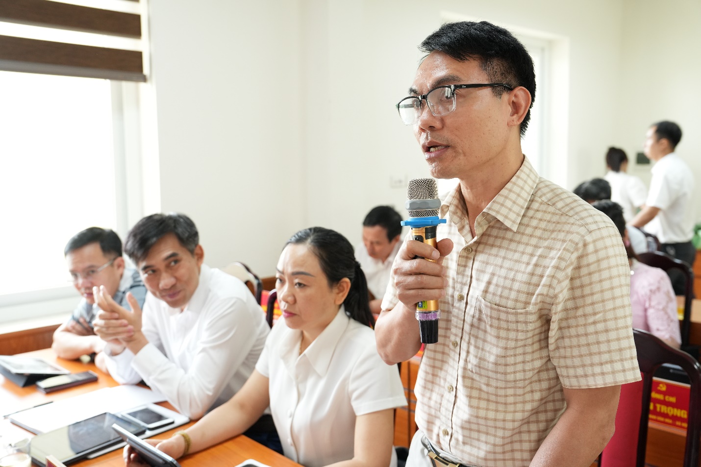 A person holding a microphone in front of a group of people  AI-generated content may be incorrect.