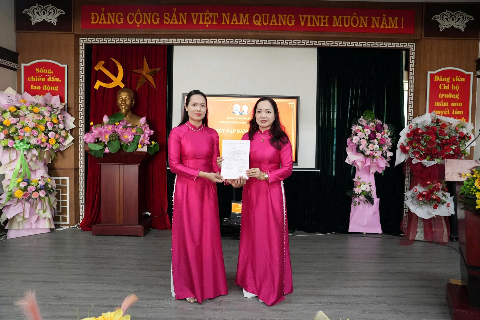 Two women in pink dresses holding a piece of paper  AI-generated content may be incorrect.